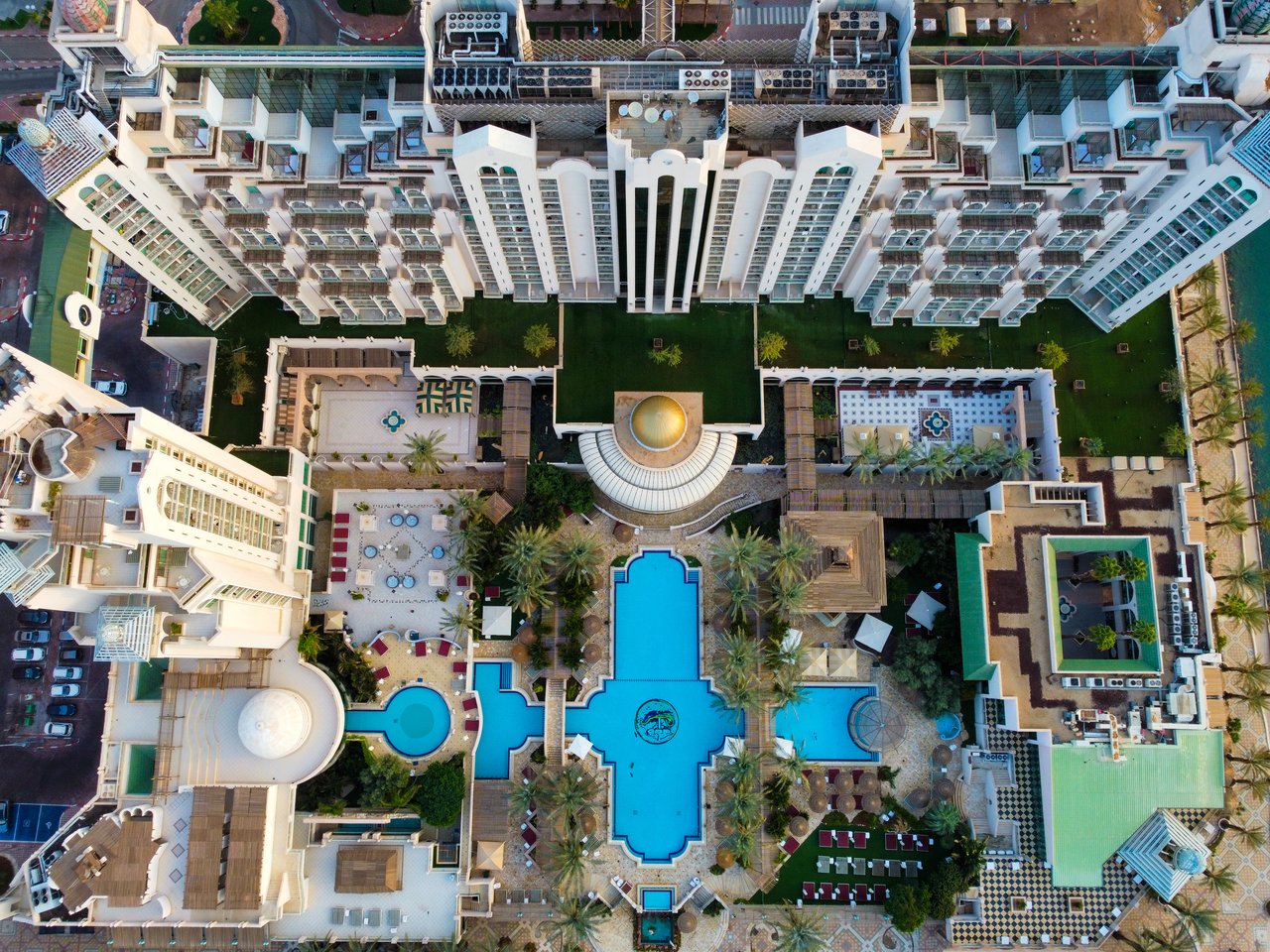 Stunning aerial view of a luxury resort featuring a large swimming pool and intricate architecture.